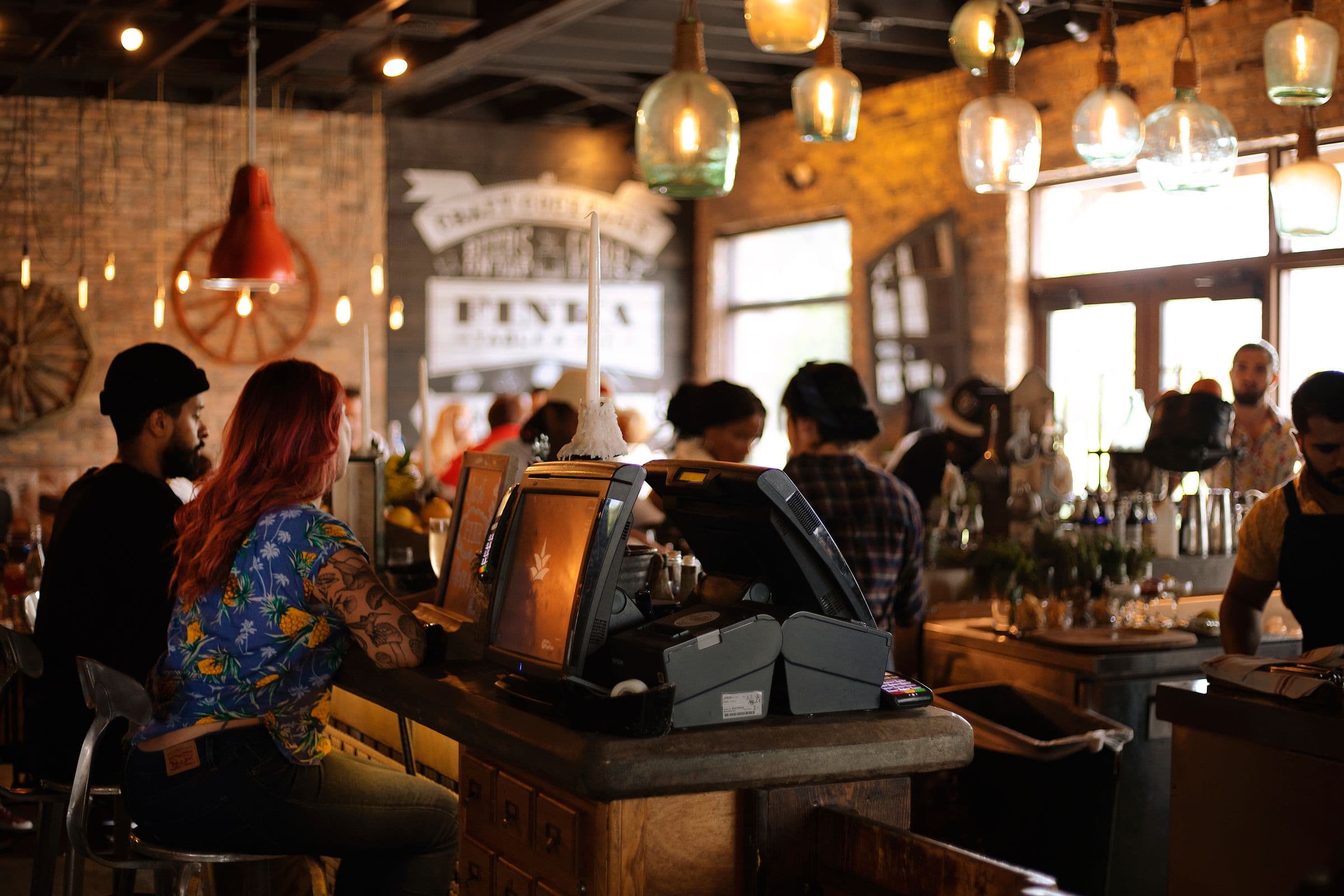 a brick and timber room under copper pendant bulbs, people at the counter