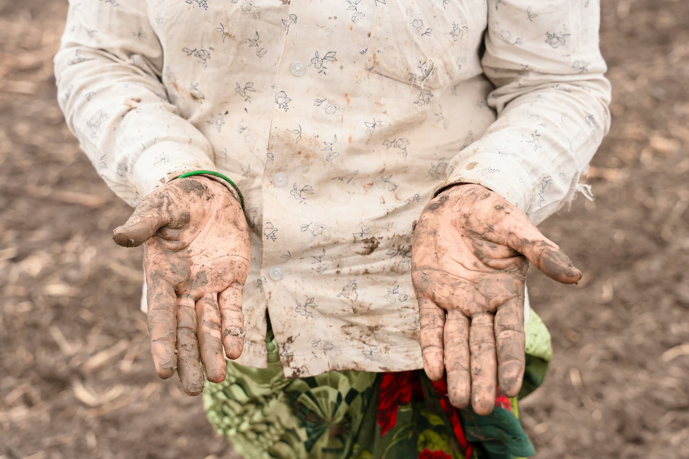 two open palms caked to the wrist in dry soil
