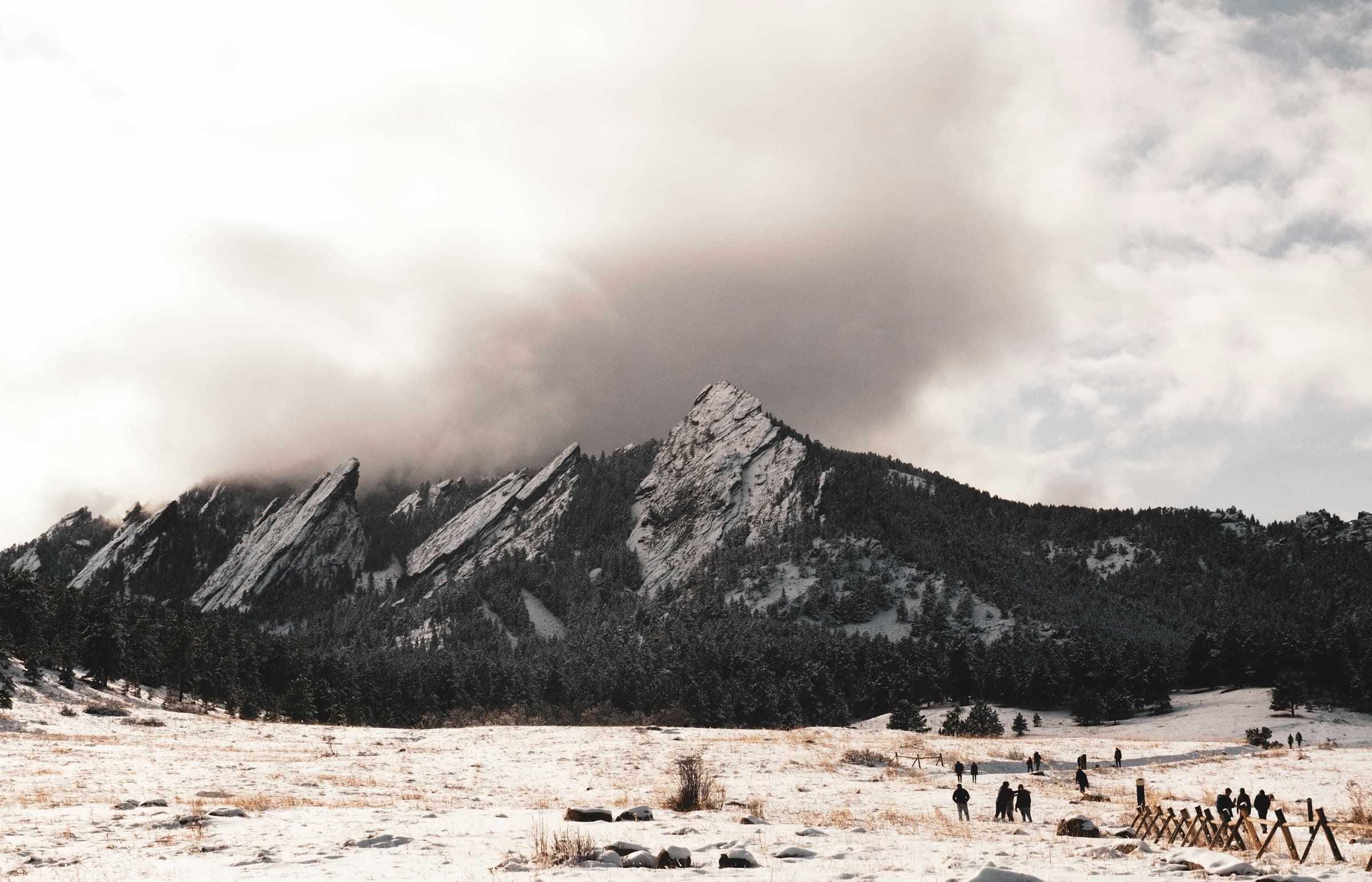 the flatirons above boulder in winter, snow on the ground, cloud breaking over the ridge